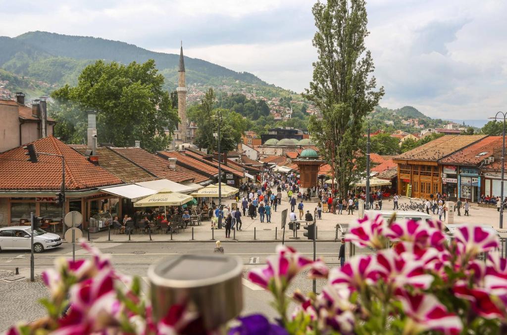 a group of people walking down a street in a town at Pigeon Square Rooms in Sarajevo