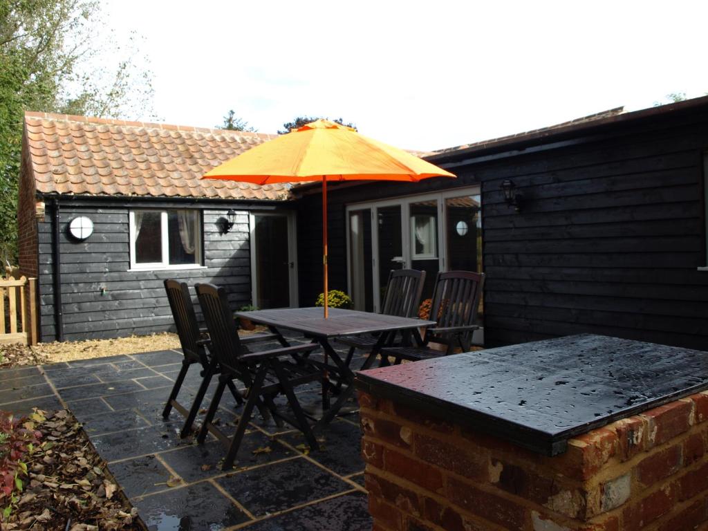 a table and chairs with an umbrella on a patio at Lakeview at Lodge Farm in Norwich