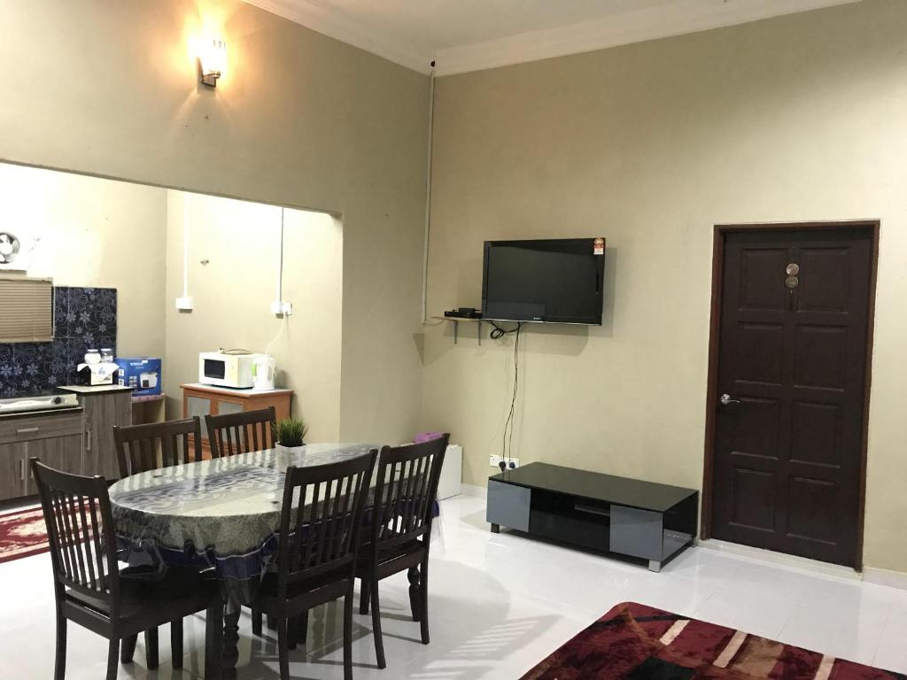 een eetkamer met een tafel en een televisie aan de muur bij Homestay HANI in Arau