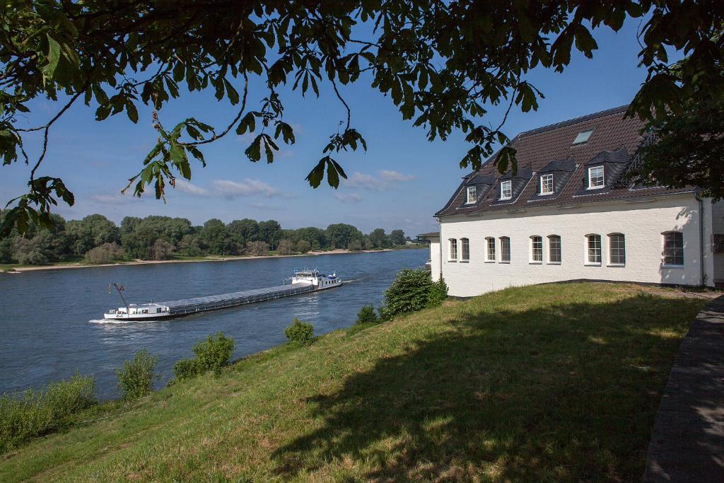 ein Boot auf dem Fluss neben einem Haus in der Unterkunft Schnellenburg in Düsseldorf