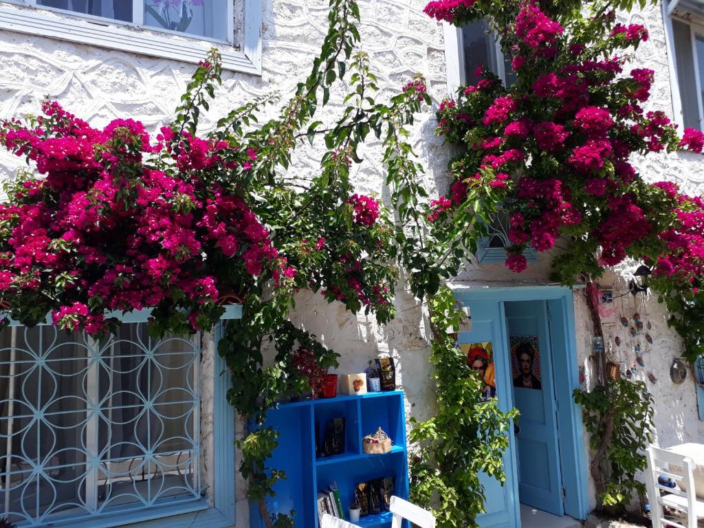 uma casa com flores cor-de-rosa e uma porta azul em Alaçatı Frida Hotel em Cesme