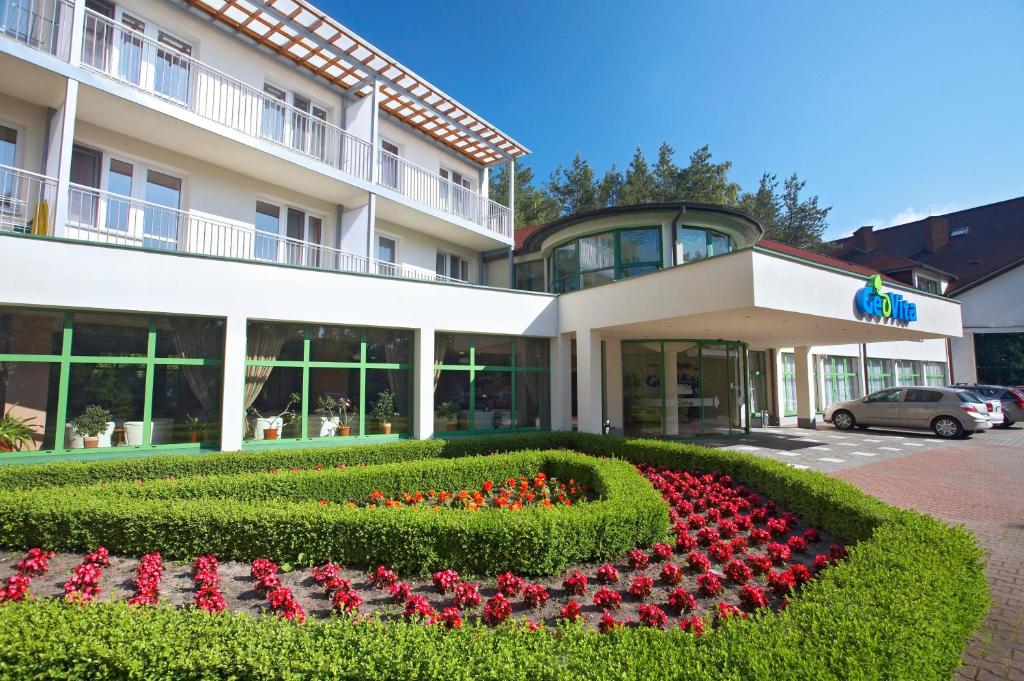 a hotel with a flower bed in front of a building at Geovita Dąbki in Dąbki