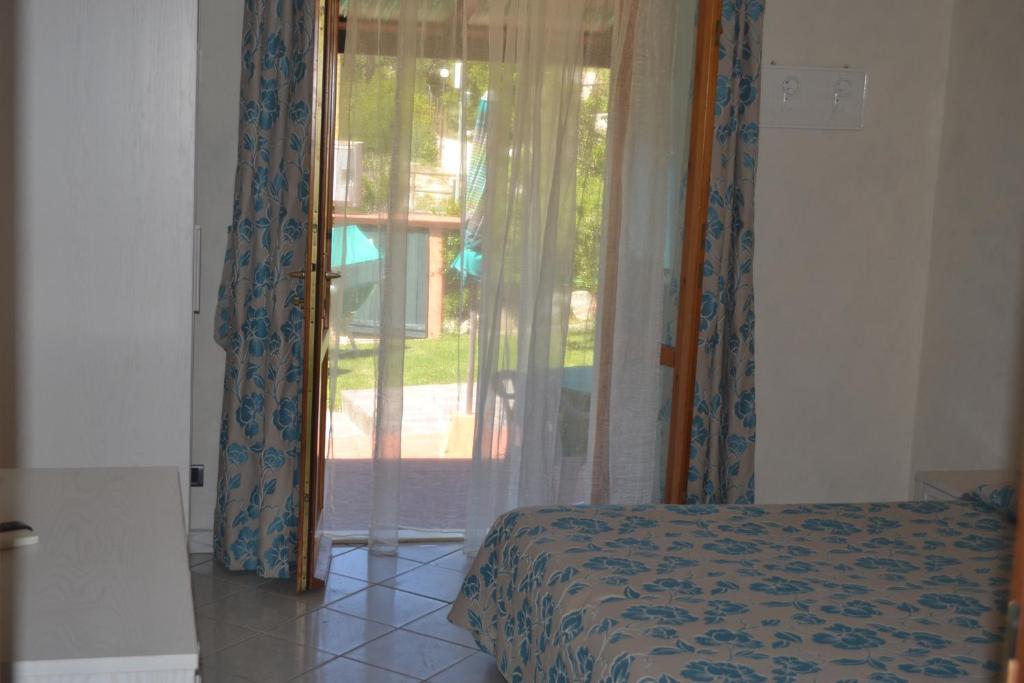 a bedroom with a bed and a sliding glass door at Hotel Danila in Portoferraio
