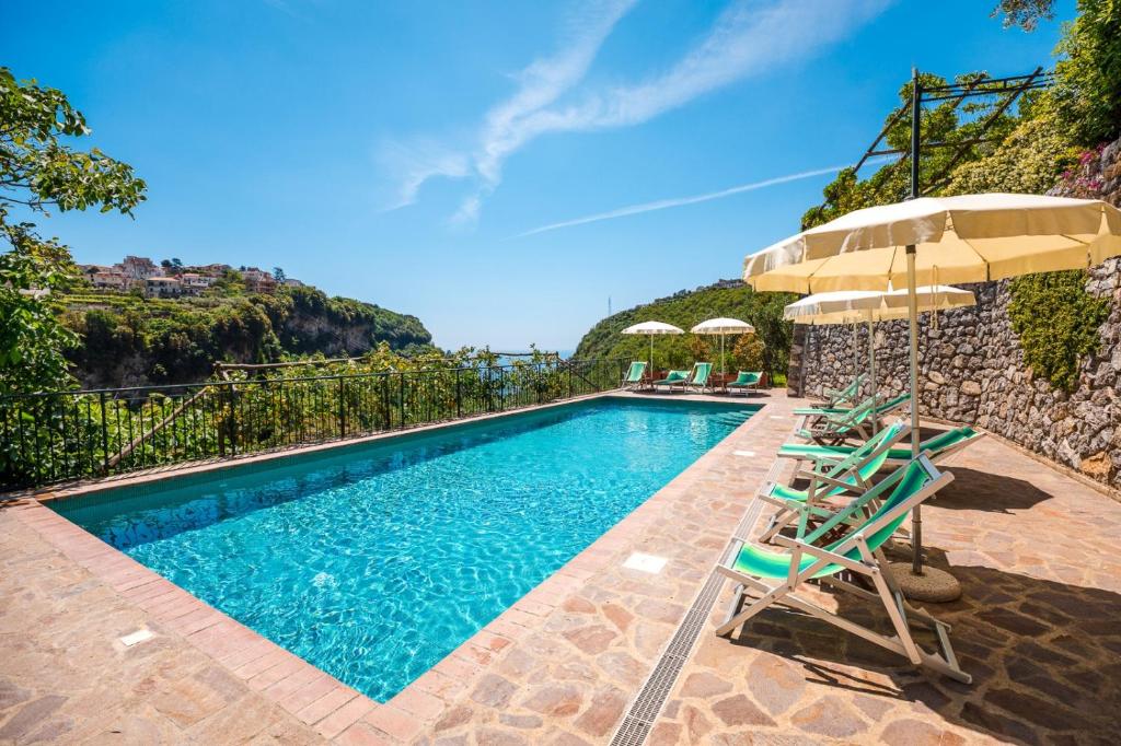 a swimming pool with chairs and umbrellas at Villa San Lorenzo in Scala