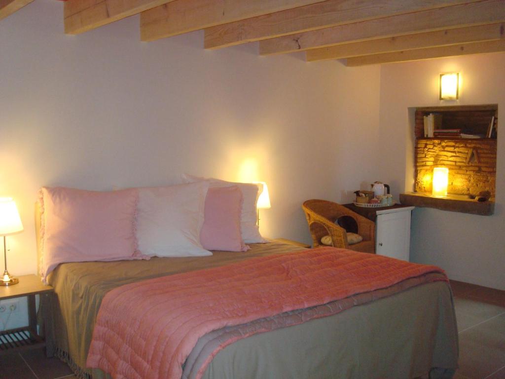 ein Schlafzimmer mit einem großen Bett mit rosa Kissen in der Unterkunft Chambre d'hôtes Les Plaisances in Saint-Julien