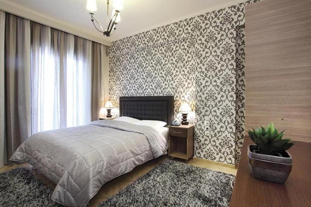 a bedroom with a bed and a patterned wall at Delfini Hotel in Menídion