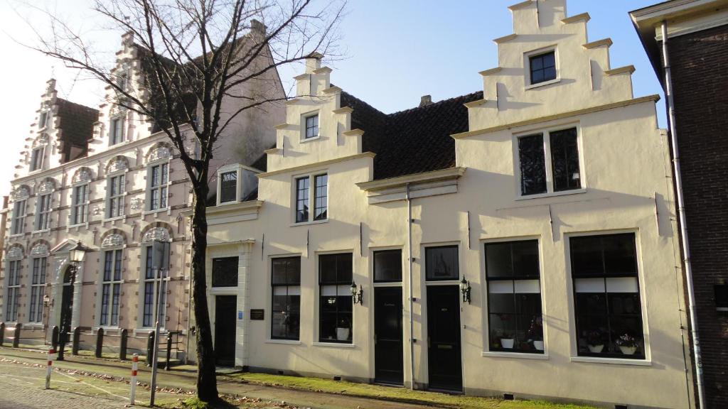 a white building with black doors on a street at Achterom 7 in Hoorn