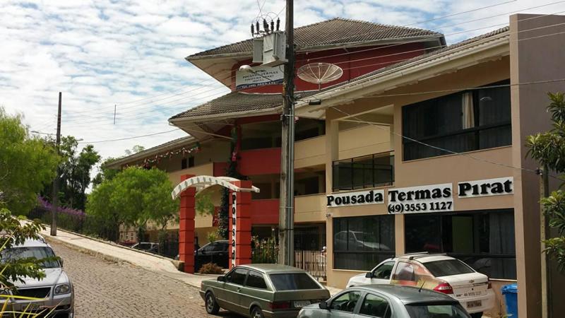 un edificio con coches estacionados frente a él en Pousada Termas Piratuba en Piratuba