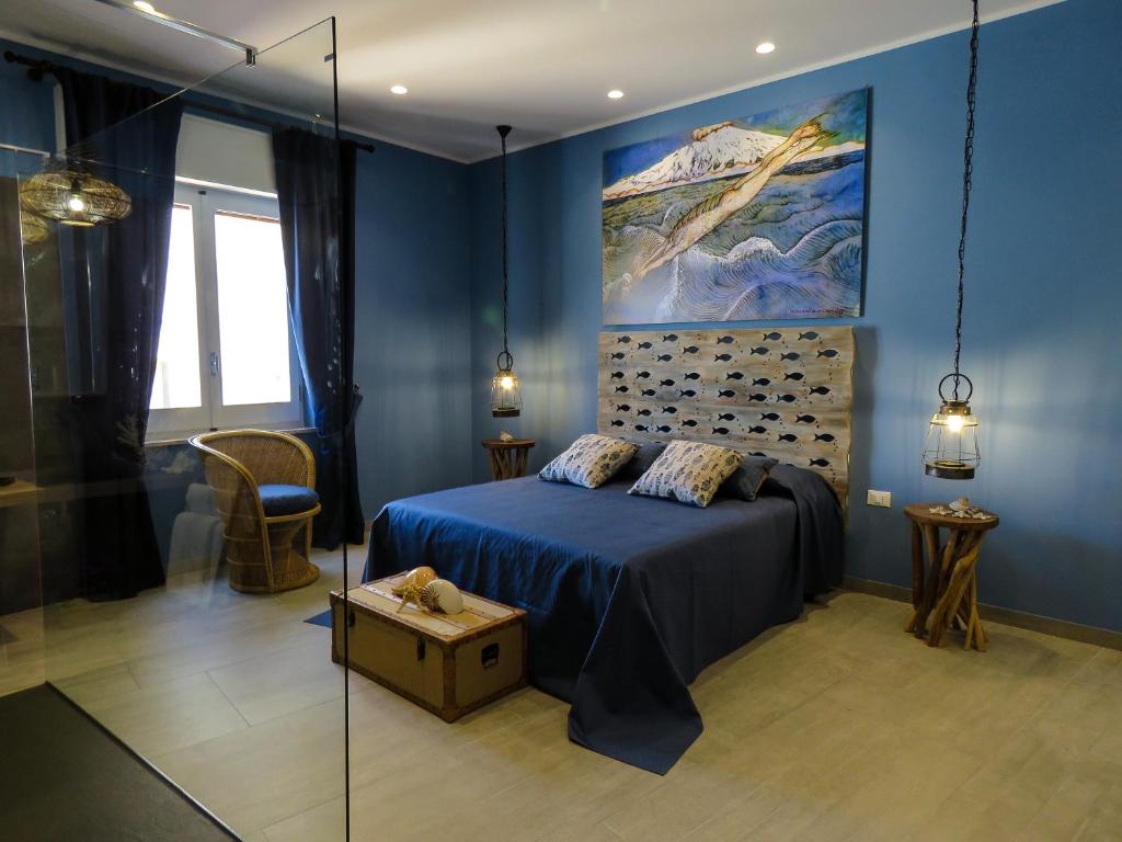 une chambre bleue avec un lit et un tableau mural dans l'établissement Catria, à Favignana