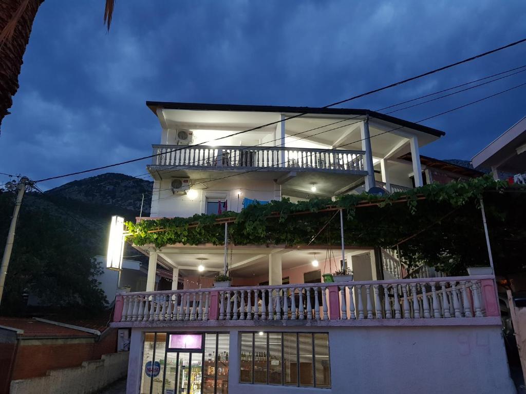 een groot wit huis met een balkon in de nacht bij Guest House Dragomir in Sutomore
