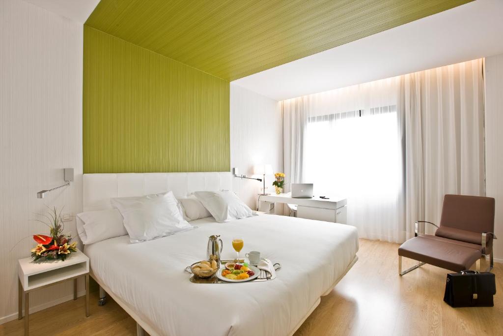 Un dormitorio con una gran cama blanca con una bandeja de comida. en Occidental Castellana Norte, en Madrid