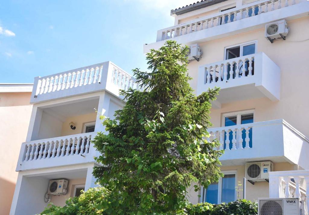 a white building with a tree in front of it at Apartments Villa Jovovic in Budva