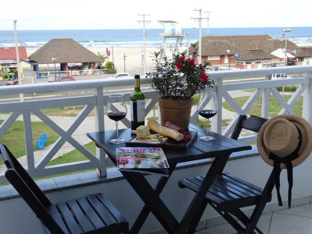 una mesa con una botella de vino y copas en el balcón en Pousada Solar Dom Kido, en Torres