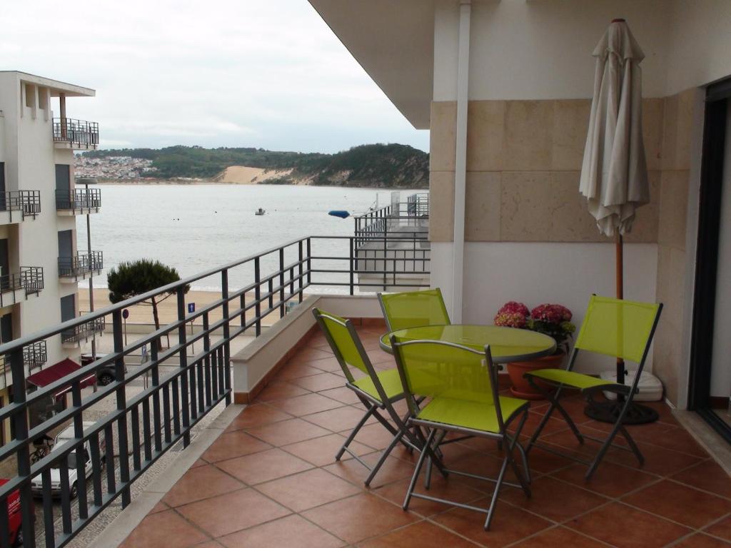 balcón con mesa, sillas y vistas al océano en Terraço da Baía en São Martinho do Porto