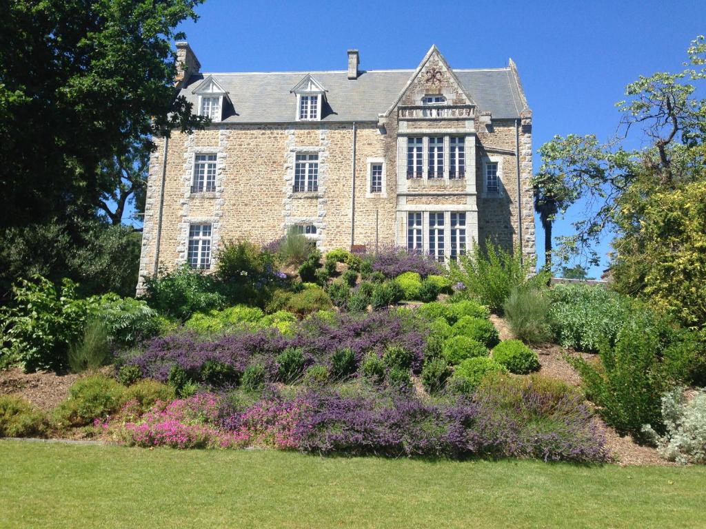 una casa antigua con un jardín delante de ella en Domaine Le Gaudin - Saint Jean le Thomas en Saint-Jean-le-Thomas