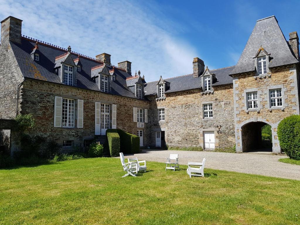 a large stone building with white chairs in the yard at Domaine du Manoir de Vains in Vains