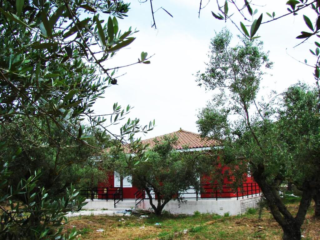 uma casa vermelha e branca com árvores em frente em Zante Green View em Ambelókipoi