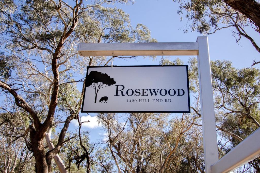 a sign for rosewood sign in front of trees at Rosewood Cottage in Grattai