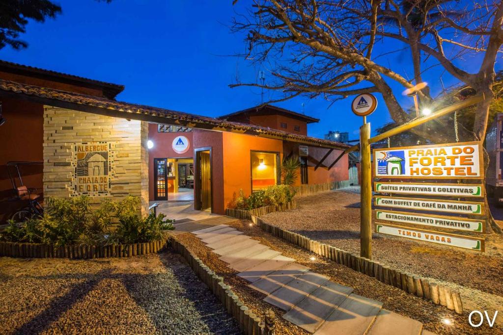 a sign in front of a building at night at Praia do Forte Hostel in Praia do Forte