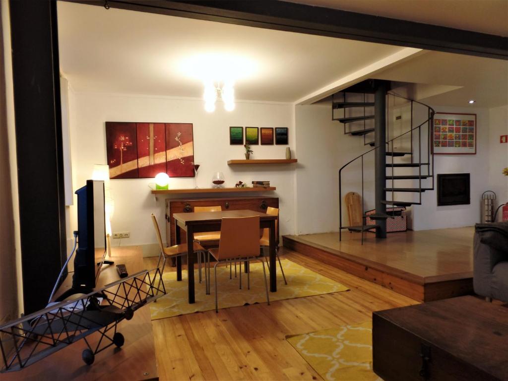 a living room with a table and a spiral staircase at Ponto de Vista - Coimbra in Coimbra