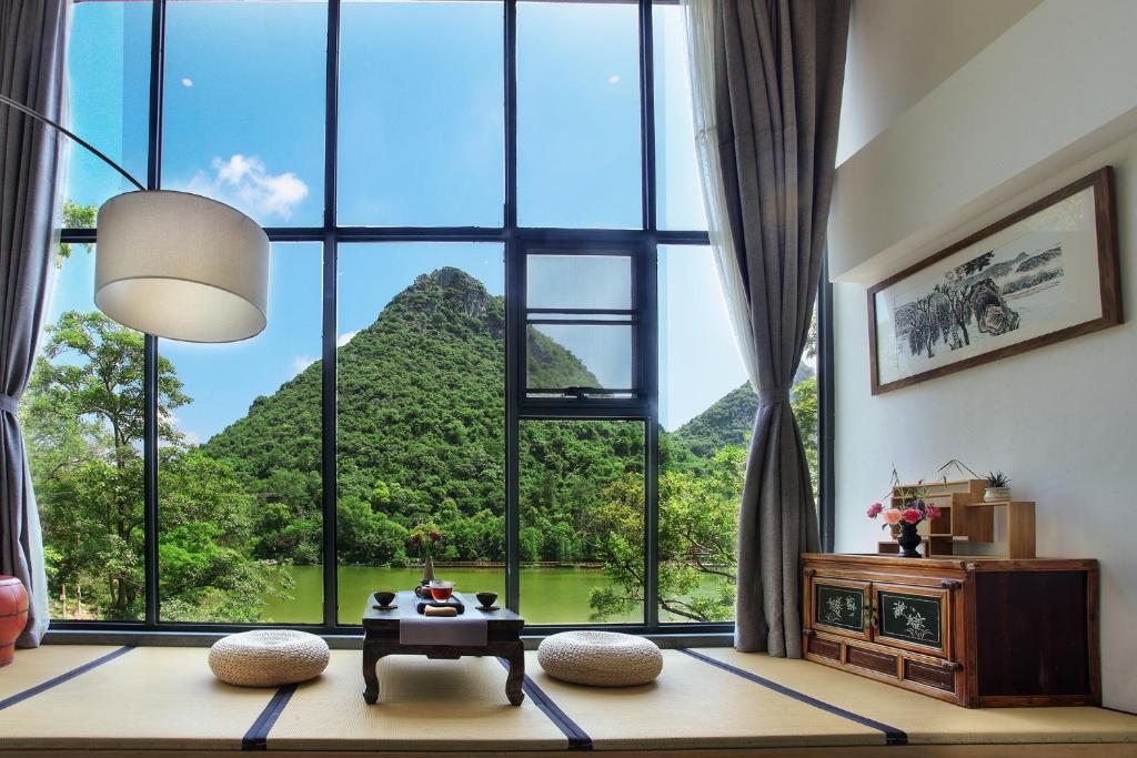 Cette chambre dispose d'une grande fenêtre offrant une vue sur la montagne. dans l'établissement Guilin HeShe Lakeside Resort, à Guilin