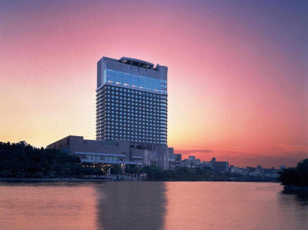 a tall building sitting on the side of a body of water at Imperial Hotel Osaka in Osaka