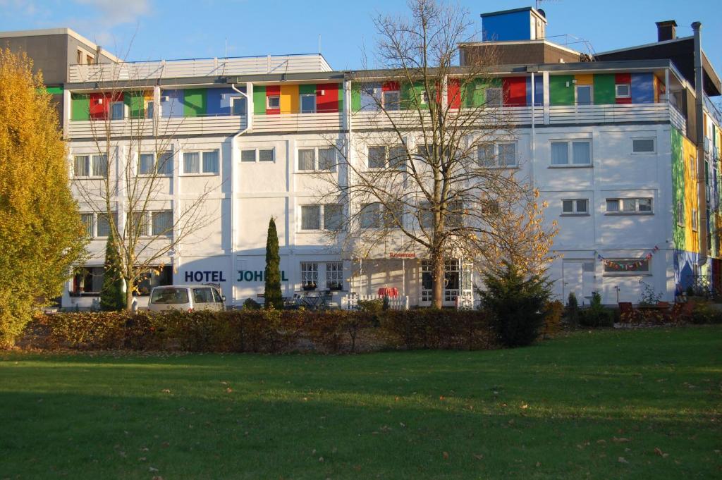 ein großes weißes Gebäude mit bunten Fenstern in einem Park in der Unterkunft Hotel Johnel in Hennef