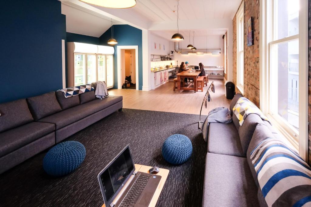 a living room with a couch and a laptop on a table at Haka House Auckland K'Road in Auckland