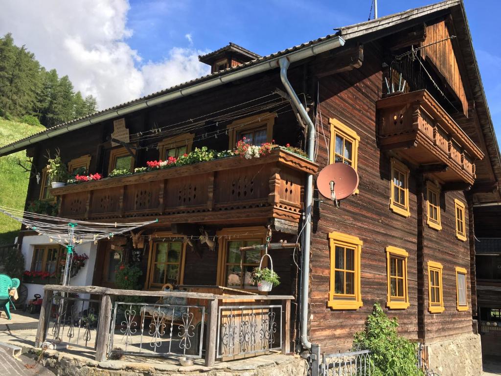 a wooden house with a balcony with flowers on it at Ferienwohnung Suntinger in Mörtschach