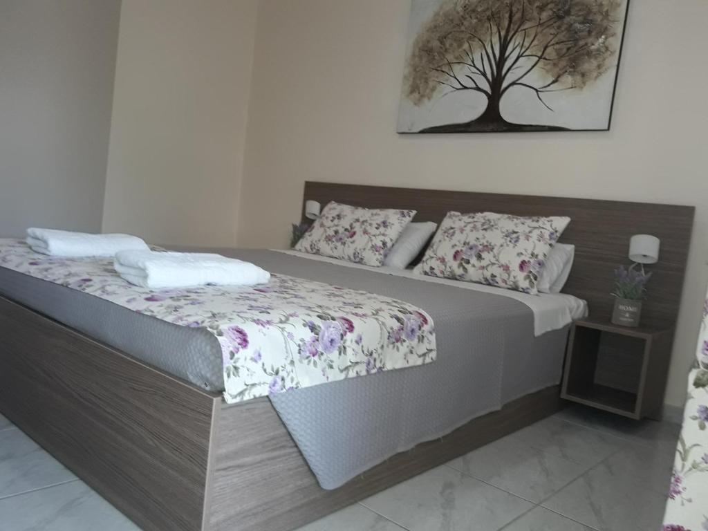 a bedroom with a bed with a tree picture on the wall at The Garden Apartments in Nea Kalikratia