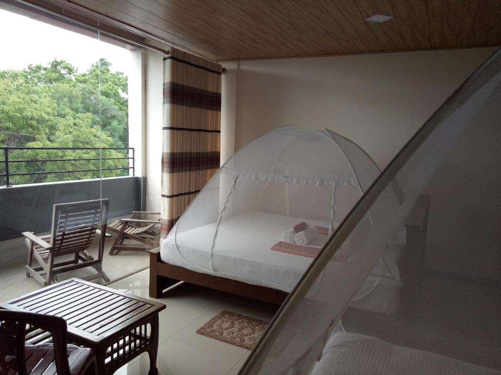 - une chambre avec un lit sur un balcon dans l'établissement Rajarata Reach Resort, à Anurâdhapura