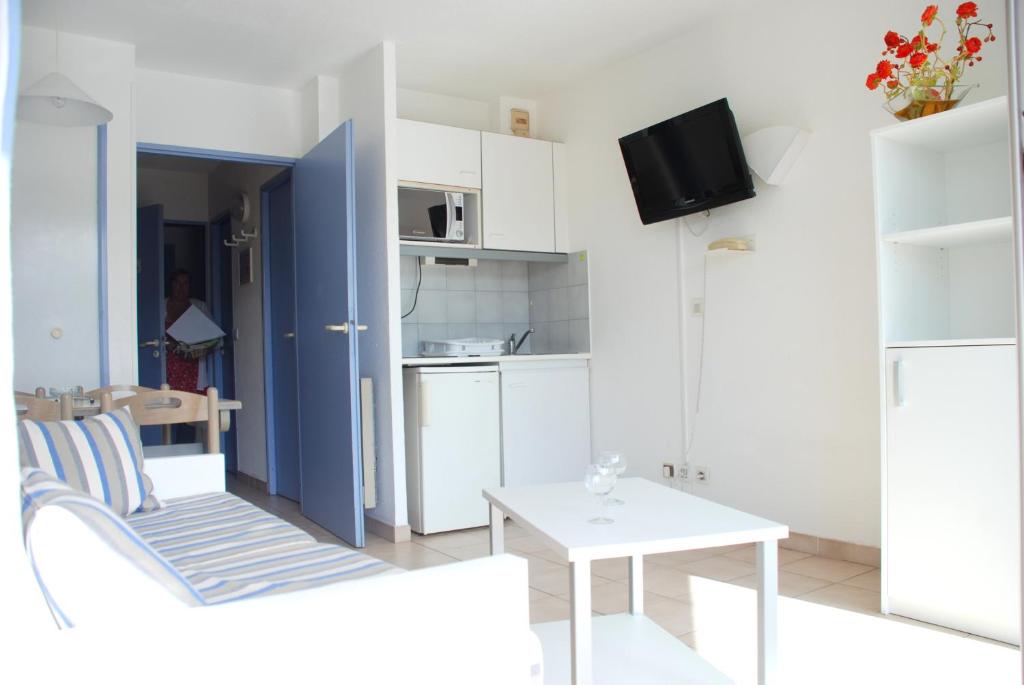 a small white kitchen with a white table and a table at Résidence Goélia Arcadius in Balaruc-les-Bains