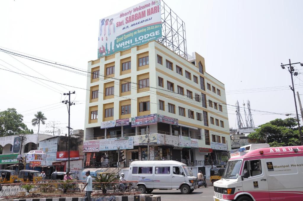 Un alto edificio bianco in una strada trafficata della città di Vani Lodge a Visakhapatnam