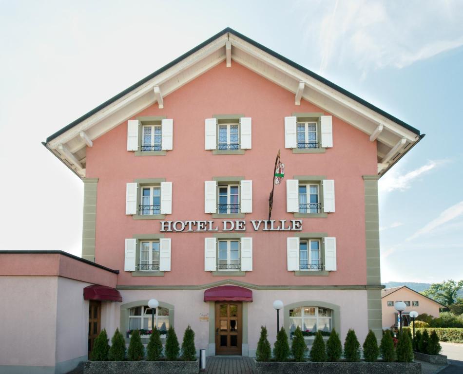 un grande edificio rosa con l'hotel de wine di Hôtel-de-Ville d'Attalens a Attalens