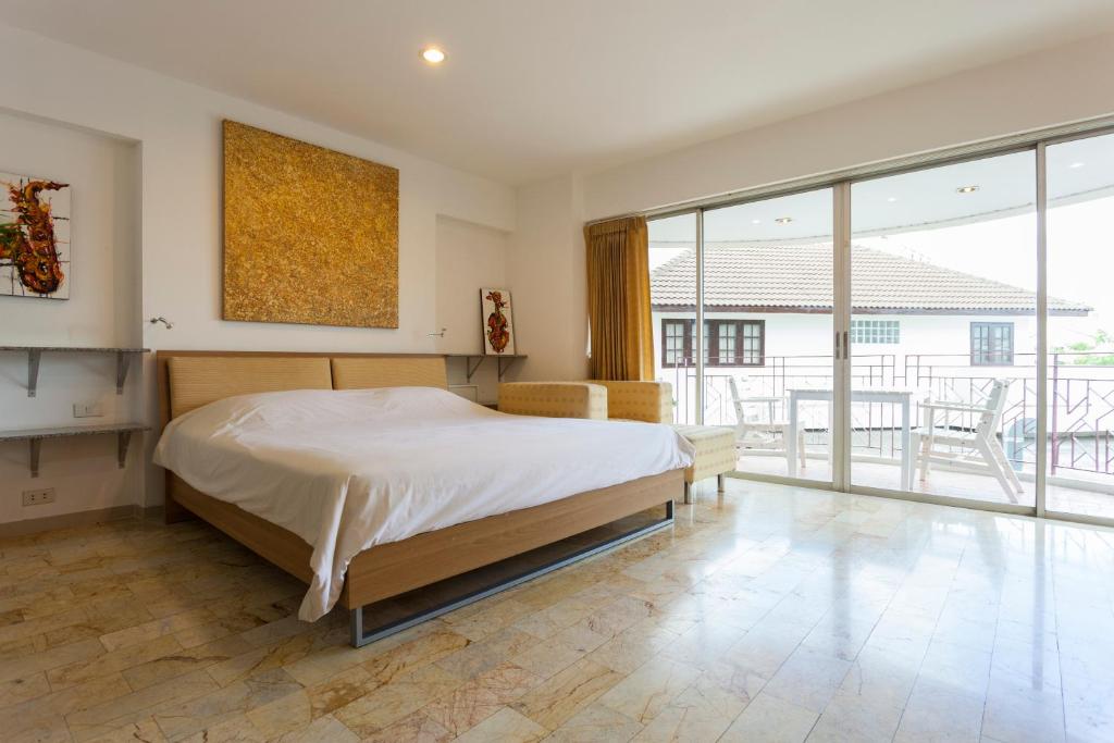 a bedroom with a large bed and large windows at Galare Thong Tower in Chiang Mai