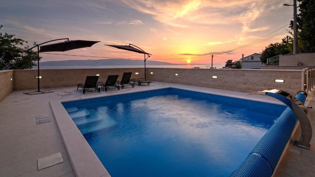 a swimming pool with a sunset in the background at Villa Karamba in Senj