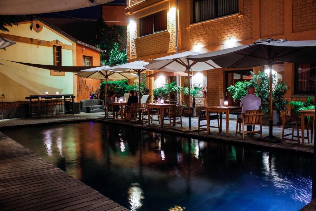 um restaurante com mesas e guarda-sóis e uma piscina em Hotel Sakamanga em Antananarivo