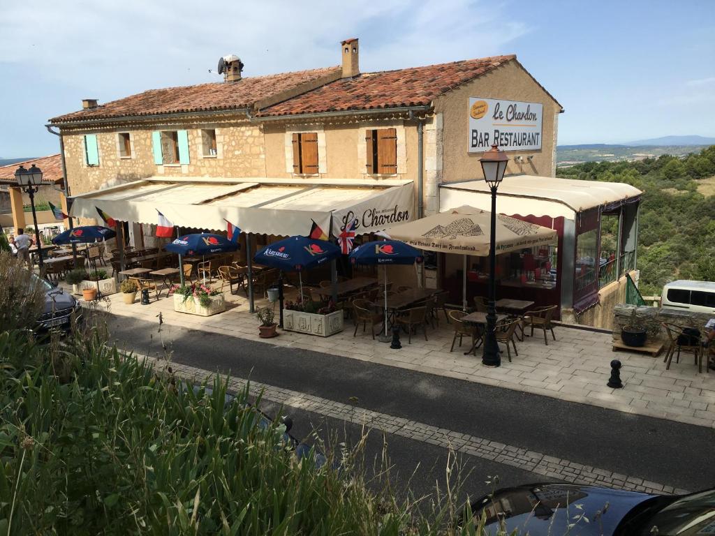 ein Gebäude mit Tischen und Sonnenschirmen auf einer Straße in der Unterkunft Le Chardon 2 in Baudinard