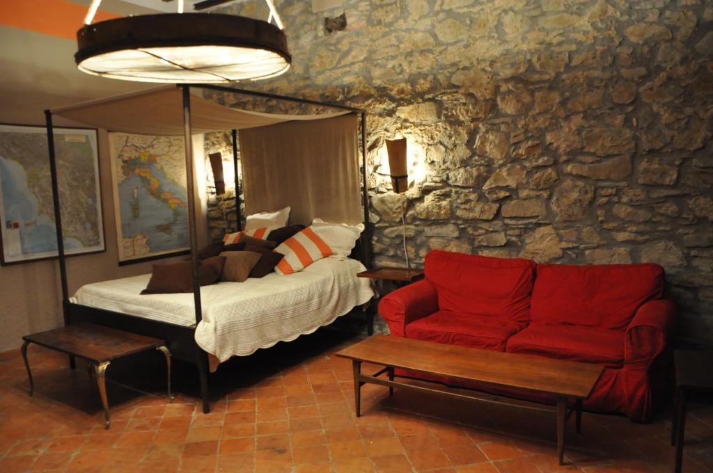 1 dormitorio con 1 cama y 1 sofá rojo en MDQ - Azienda Agricola en Castiglione dʼOrcia