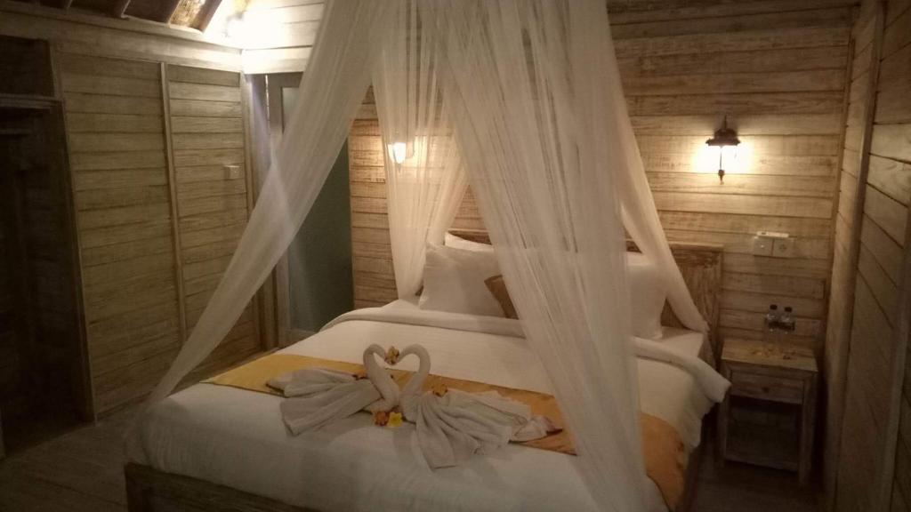 a bedroom with a bed with white curtains at Tiki bar and more in Nusa Lembongan