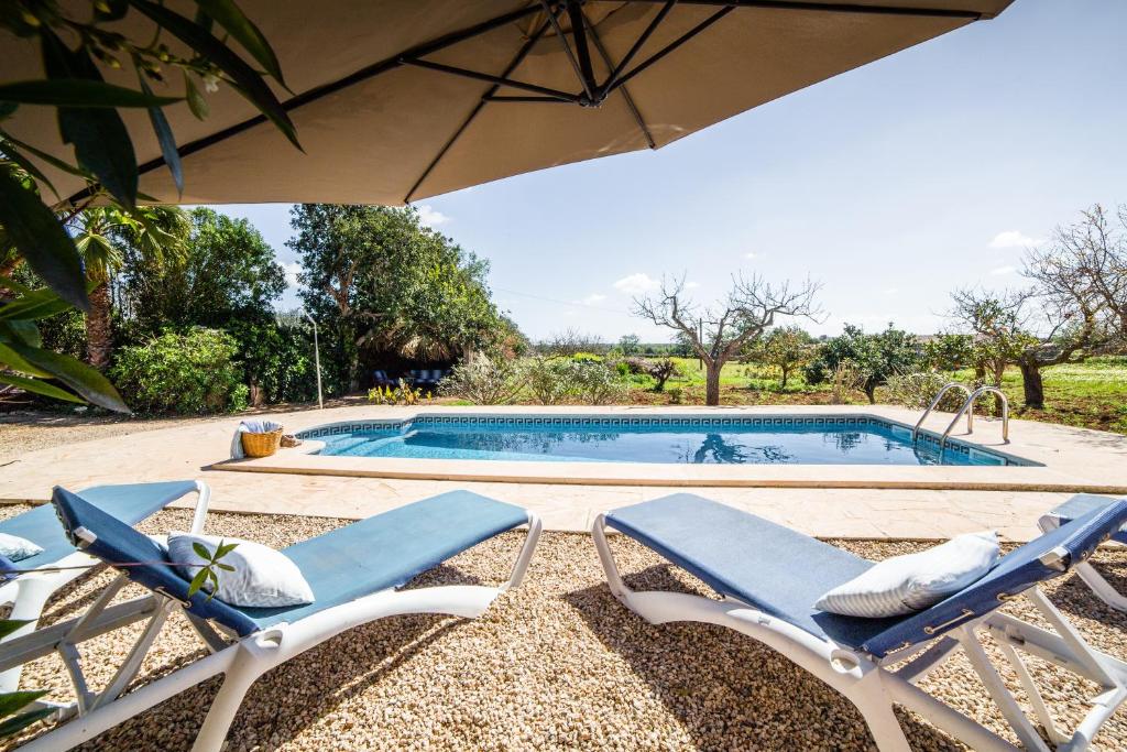 a swimming pool with two lounge chairs and an umbrella at Can Cusina in Es Llombards