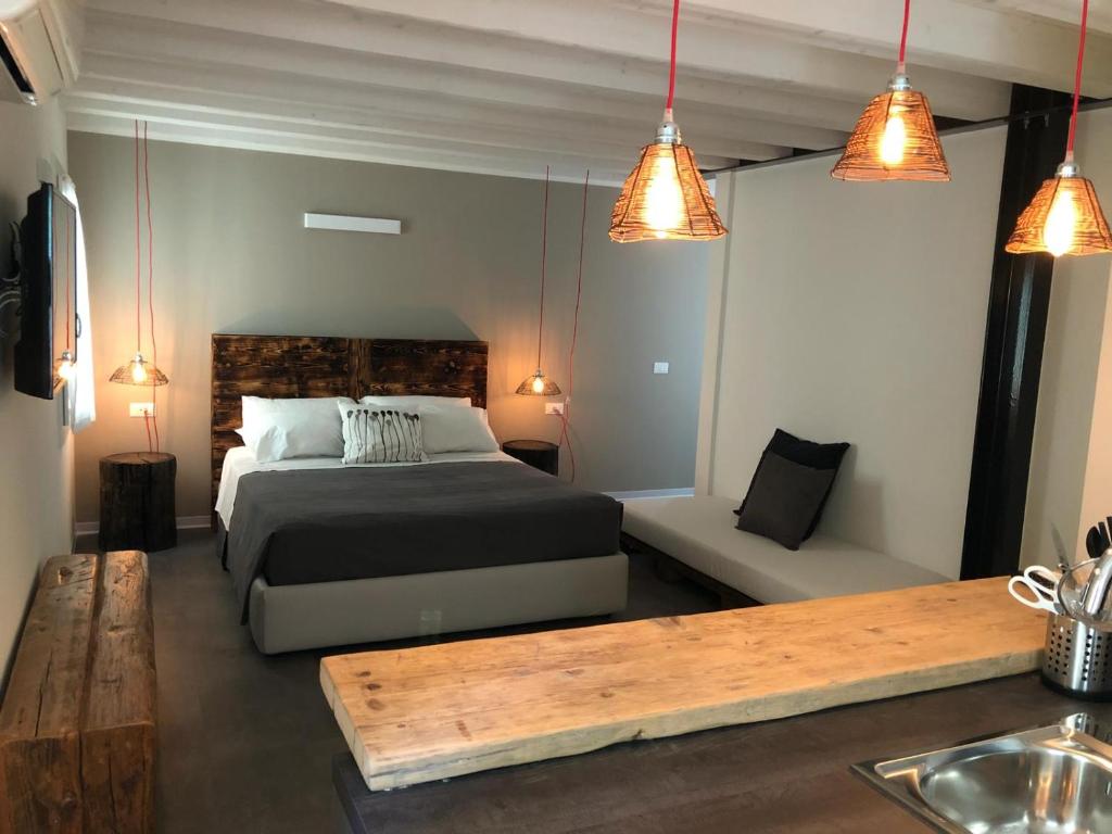 1 dormitorio con cama, mesa y luces en Kibò Urban Lodge Chioggia Adults Only, en Chioggia