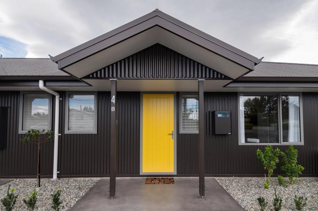 a yellow door on a black house at Luxury Rata Apartment - B in Twizel
