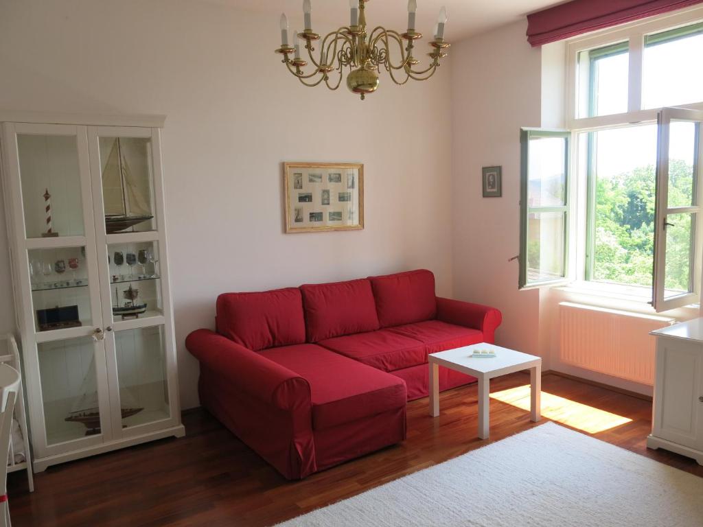 a living room with a red couch and a table at Horvath Villa Apartman Aliz in Balatonfüred