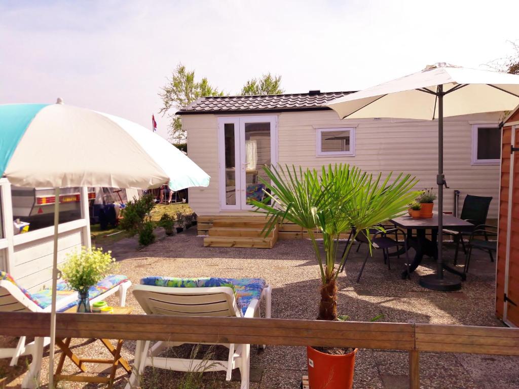 un patio con mesa, sillas y sombrilla en Chalet Dalile IJmuiden aan Zee vlakbij het strand, en IJmuiden