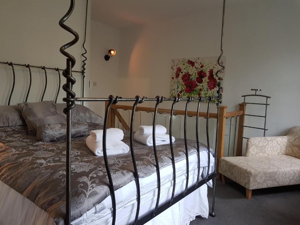 1 dormitorio con cama de metal con almohadas y silla en The Retreat at Plover Cottage Lindley, en Huddersfield