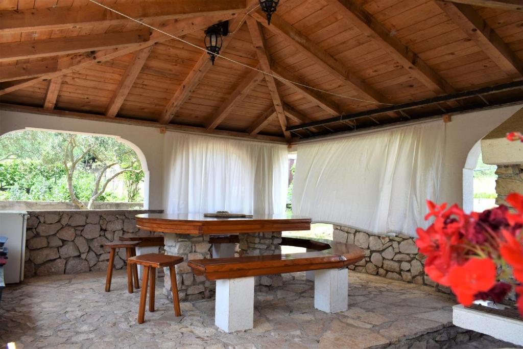 a patio with a table and a stone wall at Apartmani Erna in Pašman