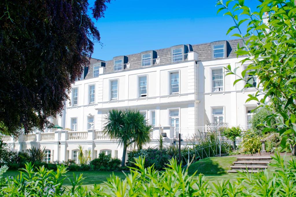 a white building with a palm tree in front of it at TLH Toorak Hotel - TLH Leisure, Entertainment and Spa Resort in Torquay