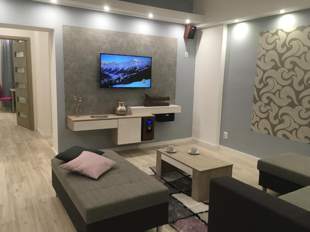 a living room with a couch and a tv on a wall at Gutenberg Apartments in Szeged