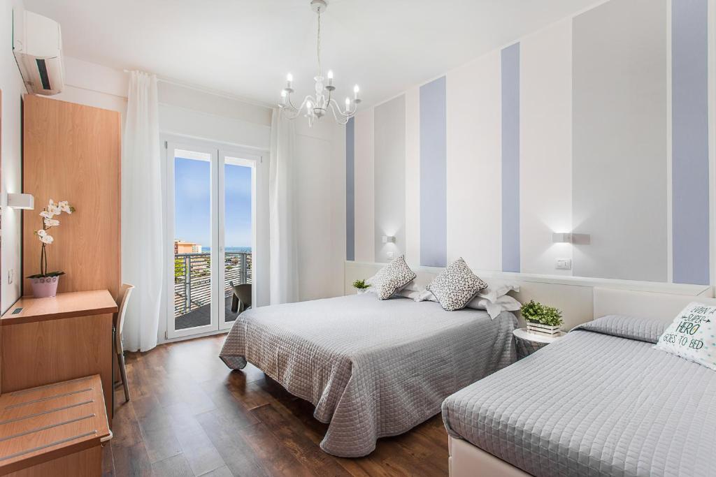 a white bedroom with two beds and a balcony at Hotel Geminus B&B in Cesenatico